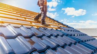 DIY metal tile roof installation, showcasing the process from underlayment application to the final placement of ridge caps on a sunny day.