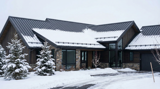 Standing seam metal roof with snow guards installed near the eaves to prevent sudden snow slides in winter.